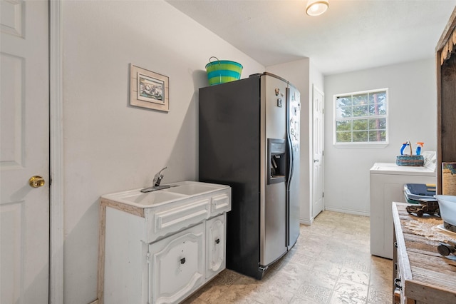 kitchen featuring stainless steel fridge with ice dispenser, washer / clothes dryer, sink, and white cabinets