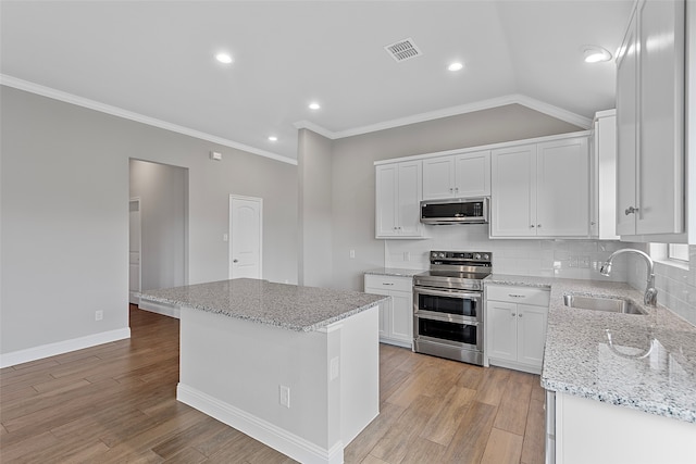 kitchen featuring white cabinets, stainless steel appliances, sink, and a kitchen island