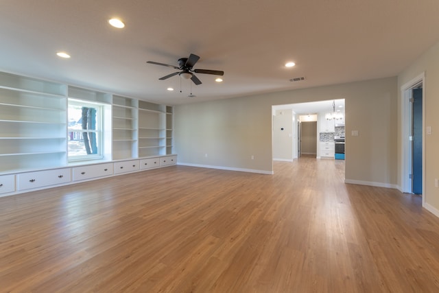 unfurnished living room with light hardwood / wood-style flooring and ceiling fan with notable chandelier