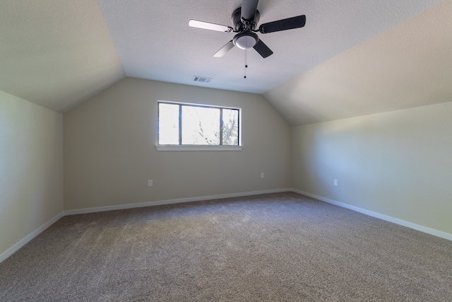 bonus room featuring lofted ceiling, a textured ceiling, carpet floors, and ceiling fan