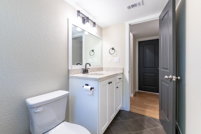 bathroom featuring toilet, a textured ceiling, vanity, and wood-type flooring