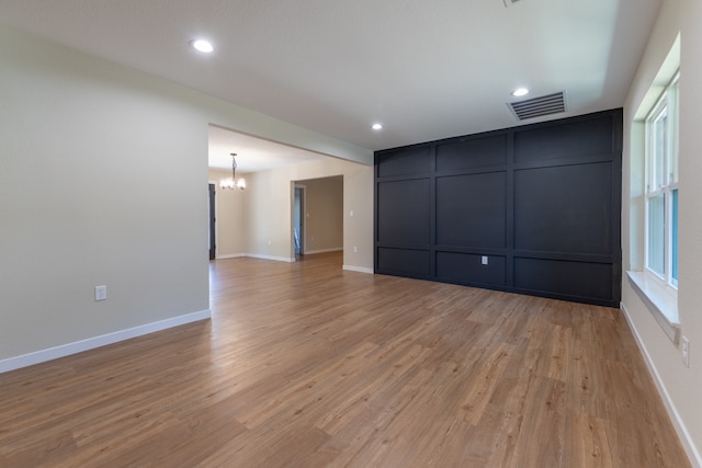 unfurnished room with light hardwood / wood-style flooring and an inviting chandelier