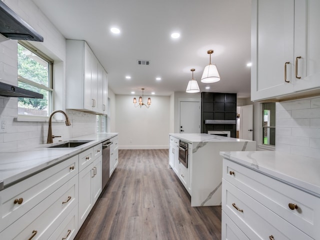 kitchen with light stone countertops, backsplash, white cabinetry, and appliances with stainless steel finishes