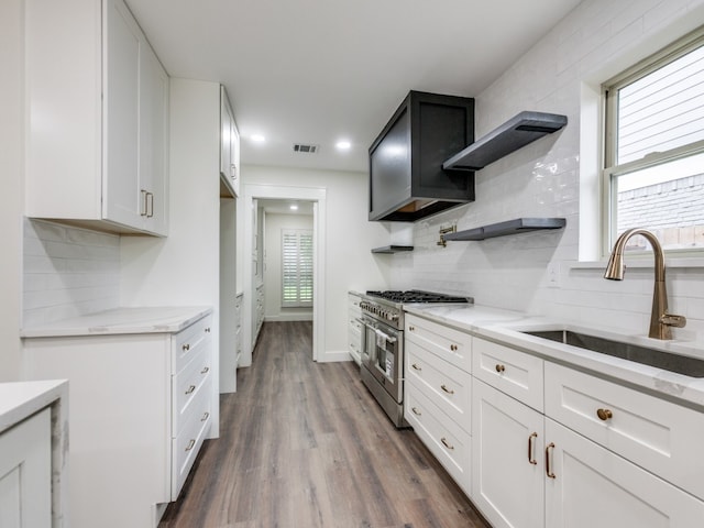 kitchen with hardwood / wood-style floors, light stone counters, white cabinetry, and double oven range