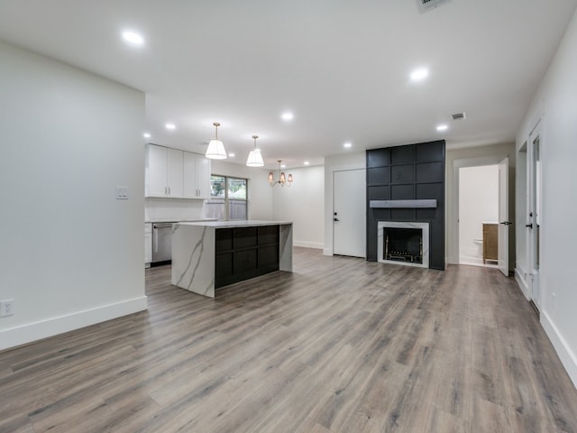 kitchen with white cabinetry, a center island, hanging light fixtures, stainless steel dishwasher, and light hardwood / wood-style floors