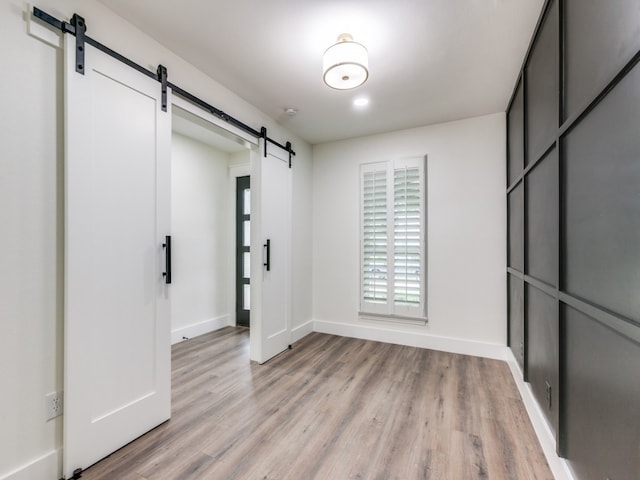 unfurnished room with a barn door and light hardwood / wood-style floors