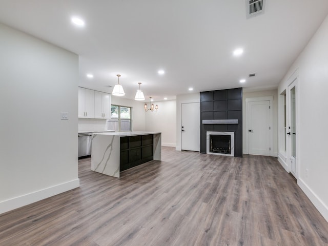 kitchen featuring decorative light fixtures, a center island, stainless steel dishwasher, white cabinetry, and light wood-type flooring