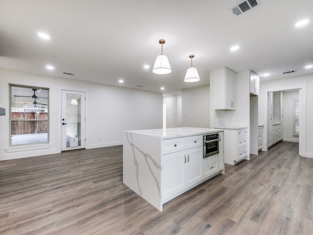 kitchen featuring white cabinetry, pendant lighting, light stone counters, and hardwood / wood-style flooring