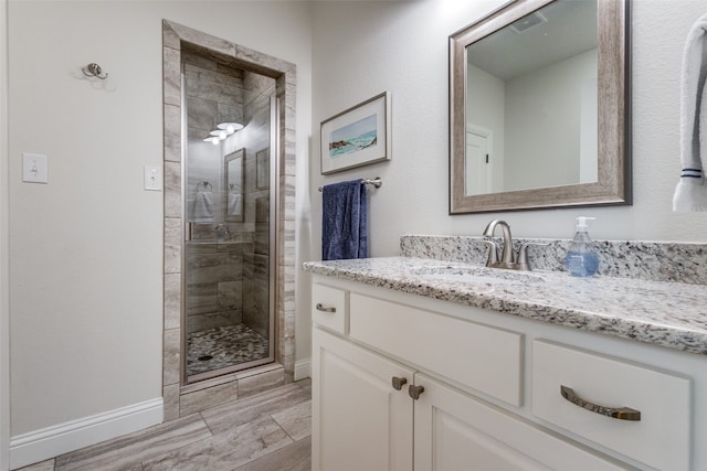 bathroom with a shower with shower door, vanity, and tile patterned floors