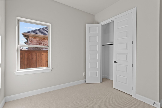 unfurnished bedroom featuring multiple windows, light carpet, and a closet