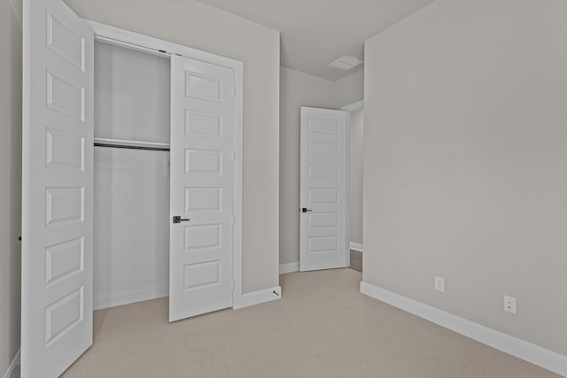 unfurnished bedroom with light colored carpet and a closet