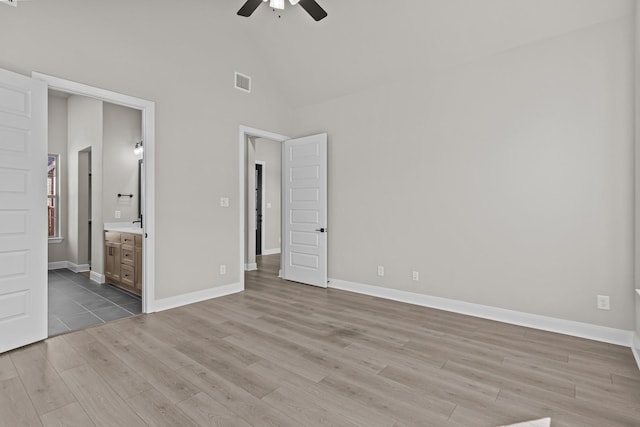 unfurnished bedroom featuring ceiling fan, ensuite bathroom, light hardwood / wood-style floors, and high vaulted ceiling