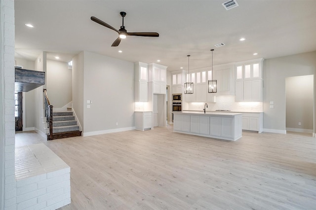 unfurnished living room with sink, light hardwood / wood-style floors, and ceiling fan