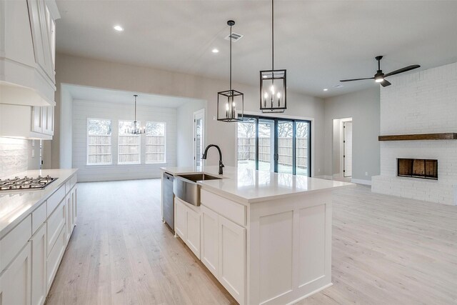 kitchen featuring premium range hood, appliances with stainless steel finishes, tasteful backsplash, white cabinetry, and light hardwood / wood-style floors