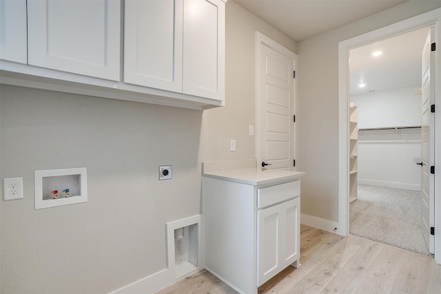 laundry room with hookup for a washing machine, electric dryer hookup, light wood-type flooring, and cabinets