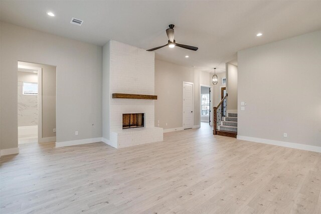 kitchen featuring decorative light fixtures, light hardwood / wood-style flooring, a center island with sink, decorative backsplash, and white cabinets