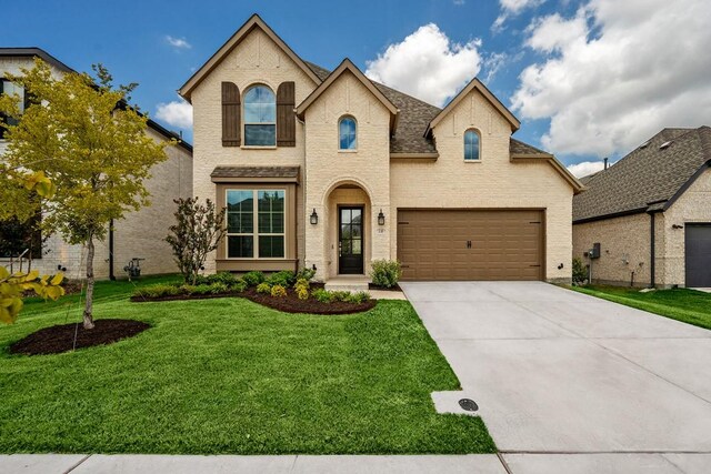 french country style house featuring a garage and a front lawn