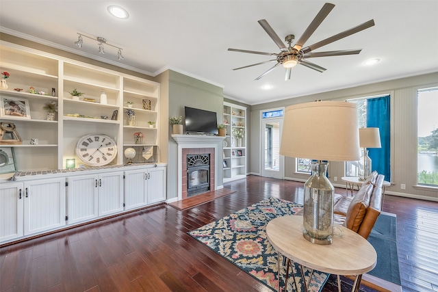 living room with track lighting, hardwood / wood-style flooring, a fireplace, ceiling fan, and ornamental molding