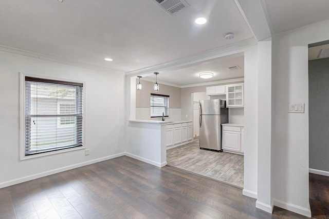 kitchen featuring white cabinets, stainless steel refrigerator, dark hardwood / wood-style flooring, crown molding, and decorative light fixtures