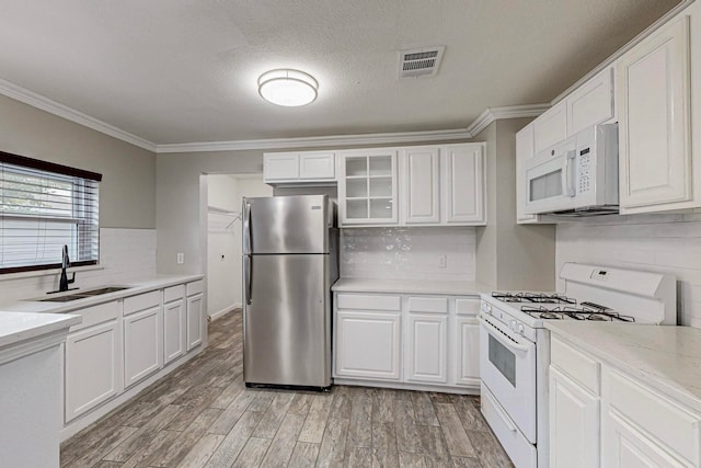 kitchen with white cabinetry, white appliances, crown molding, light hardwood / wood-style flooring, and sink