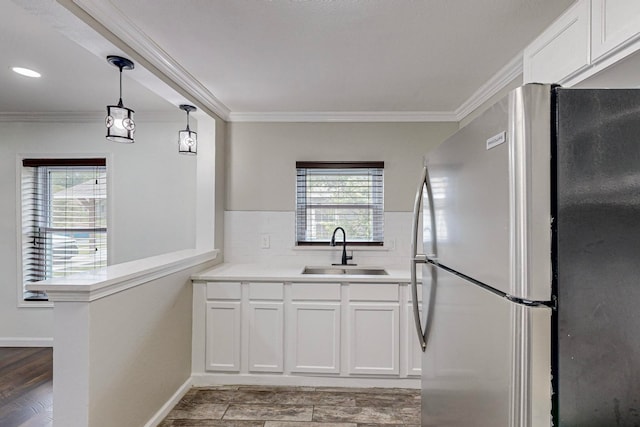 kitchen with a wealth of natural light, white cabinets, sink, and stainless steel fridge