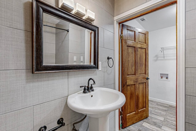 bathroom with hardwood / wood-style flooring, tile walls, and sink