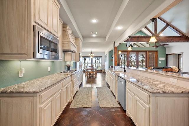 kitchen featuring ceiling fan with notable chandelier, light stone counters, dark tile patterned floors, beamed ceiling, and stainless steel appliances