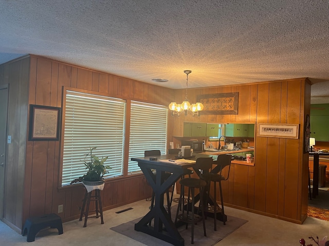 dining room with light colored carpet, a chandelier, and a textured ceiling