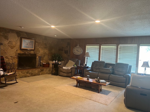 carpeted living room featuring a fireplace, wood walls, and a textured ceiling