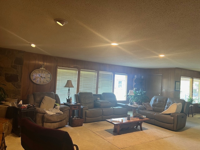 living room with carpet floors, a textured ceiling, wooden walls, and plenty of natural light