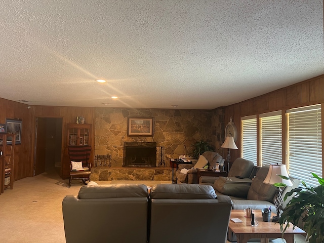 carpeted living room with a stone fireplace, wooden walls, and a textured ceiling