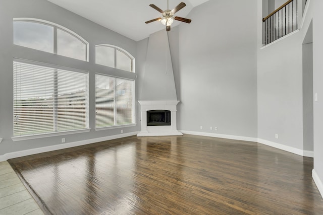 unfurnished living room featuring a wealth of natural light, high vaulted ceiling, dark hardwood / wood-style floors, and ceiling fan