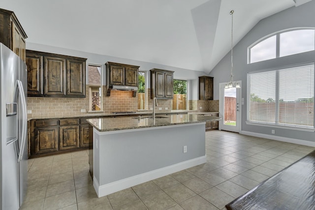 kitchen featuring stainless steel appliances, light tile patterned flooring, hanging light fixtures, and a center island with sink