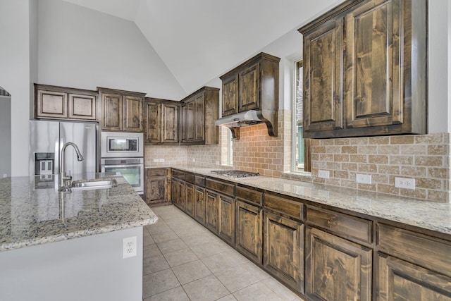 kitchen with sink, decorative backsplash, light tile patterned floors, light stone counters, and stainless steel appliances