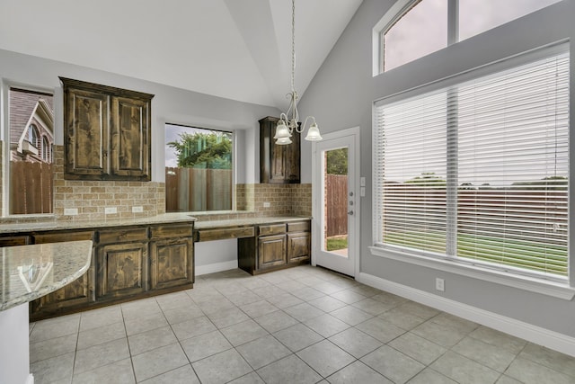 kitchen featuring an inviting chandelier, tasteful backsplash, light stone countertops, light tile patterned flooring, and decorative light fixtures