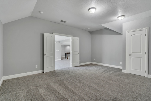 unfurnished bedroom with vaulted ceiling, a textured ceiling, and carpet