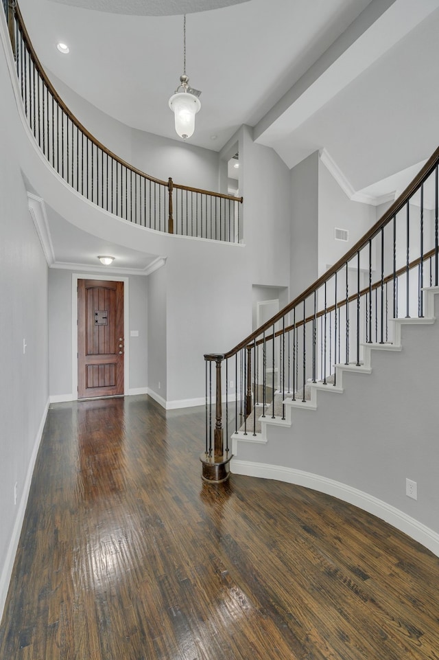 foyer featuring dark wood-type flooring, ornamental molding, and high vaulted ceiling