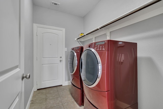 clothes washing area with washer and clothes dryer and light tile patterned floors