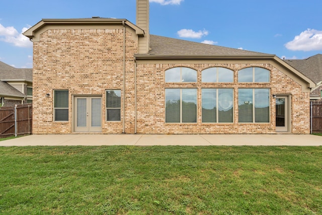 rear view of house featuring a lawn, french doors, and a patio area