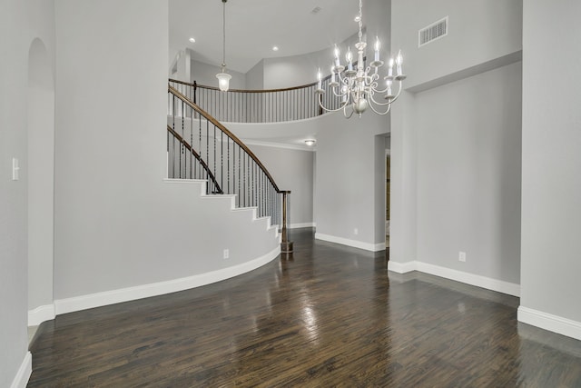 interior space with dark hardwood / wood-style flooring, a towering ceiling, and a chandelier