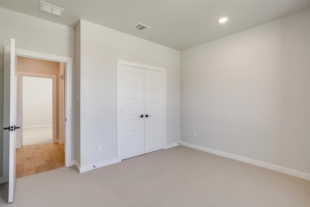 unfurnished bedroom with a closet and light colored carpet