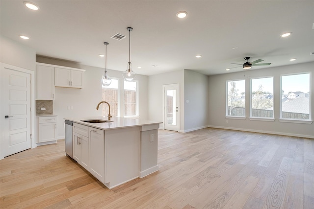 kitchen with white cabinetry, a healthy amount of sunlight, sink, and a center island with sink