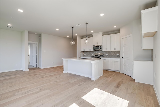 kitchen with decorative light fixtures, white cabinets, stainless steel appliances, and light wood-type flooring