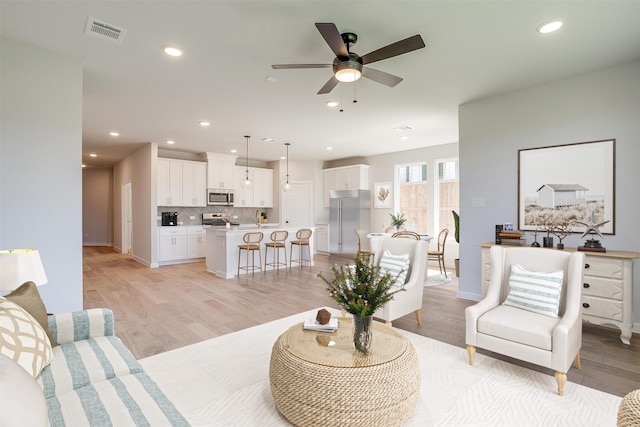 living room featuring ceiling fan and light wood-type flooring