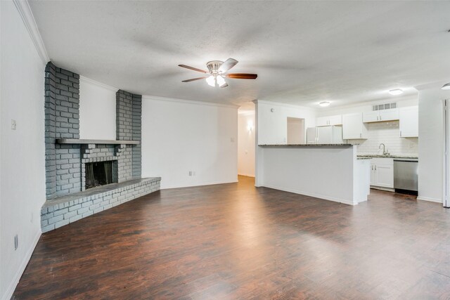 unfurnished living room featuring a textured ceiling, dark hardwood / wood-style flooring, ceiling fan, a fireplace, and ornamental molding