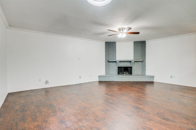 unfurnished living room with a fireplace, wood-type flooring, ceiling fan, crown molding, and brick wall