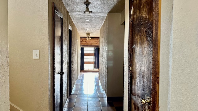 hallway with a textured ceiling and tile patterned flooring