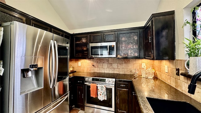 kitchen with appliances with stainless steel finishes, dark brown cabinetry, vaulted ceiling, and decorative backsplash