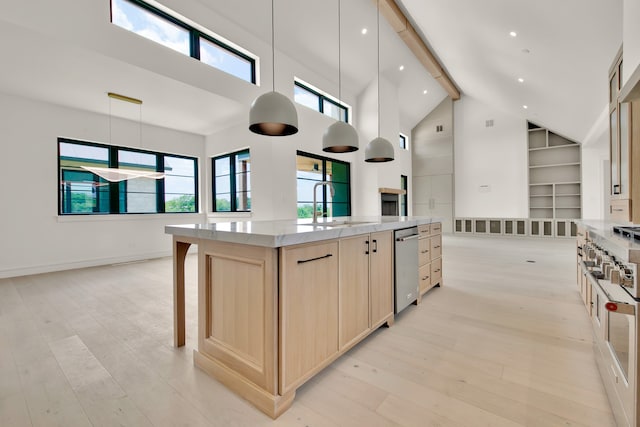 kitchen featuring light brown cabinets, hanging light fixtures, high vaulted ceiling, a spacious island, and light wood-type flooring