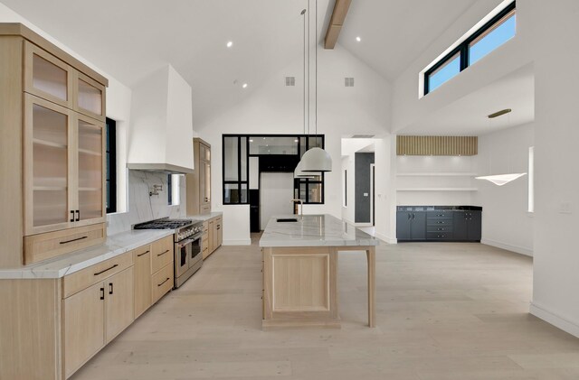 kitchen featuring beam ceiling, light hardwood / wood-style flooring, high vaulted ceiling, a spacious island, and range with two ovens